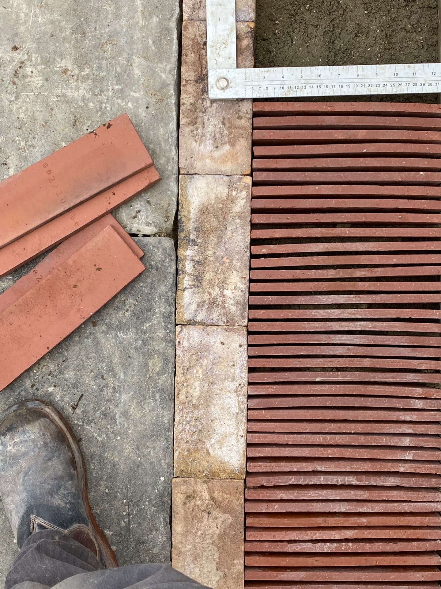 Setting red brick slips on edge against a stone border with a measuring square