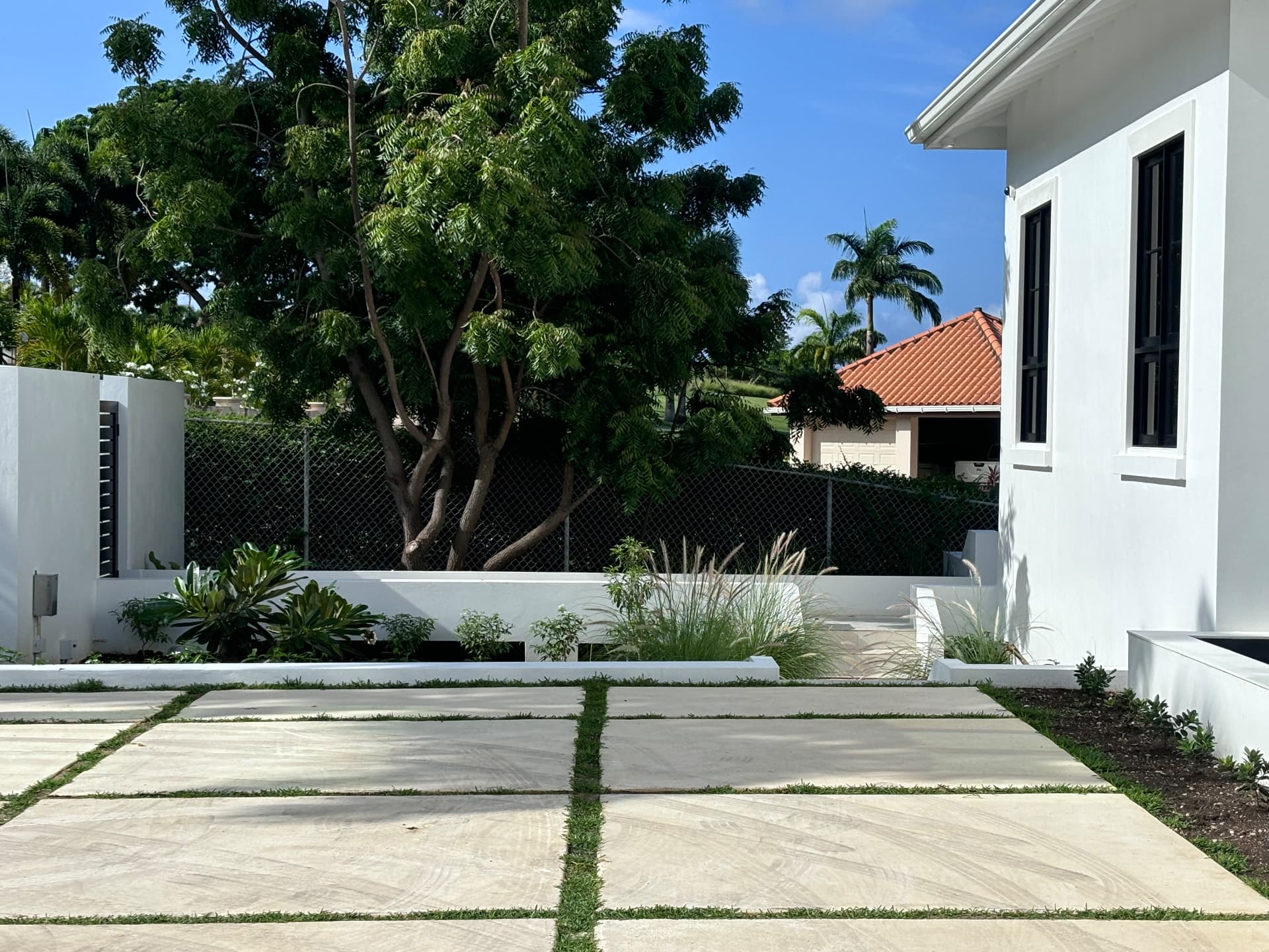 Large stone paving with grass joints leading past planting to the villa entrance