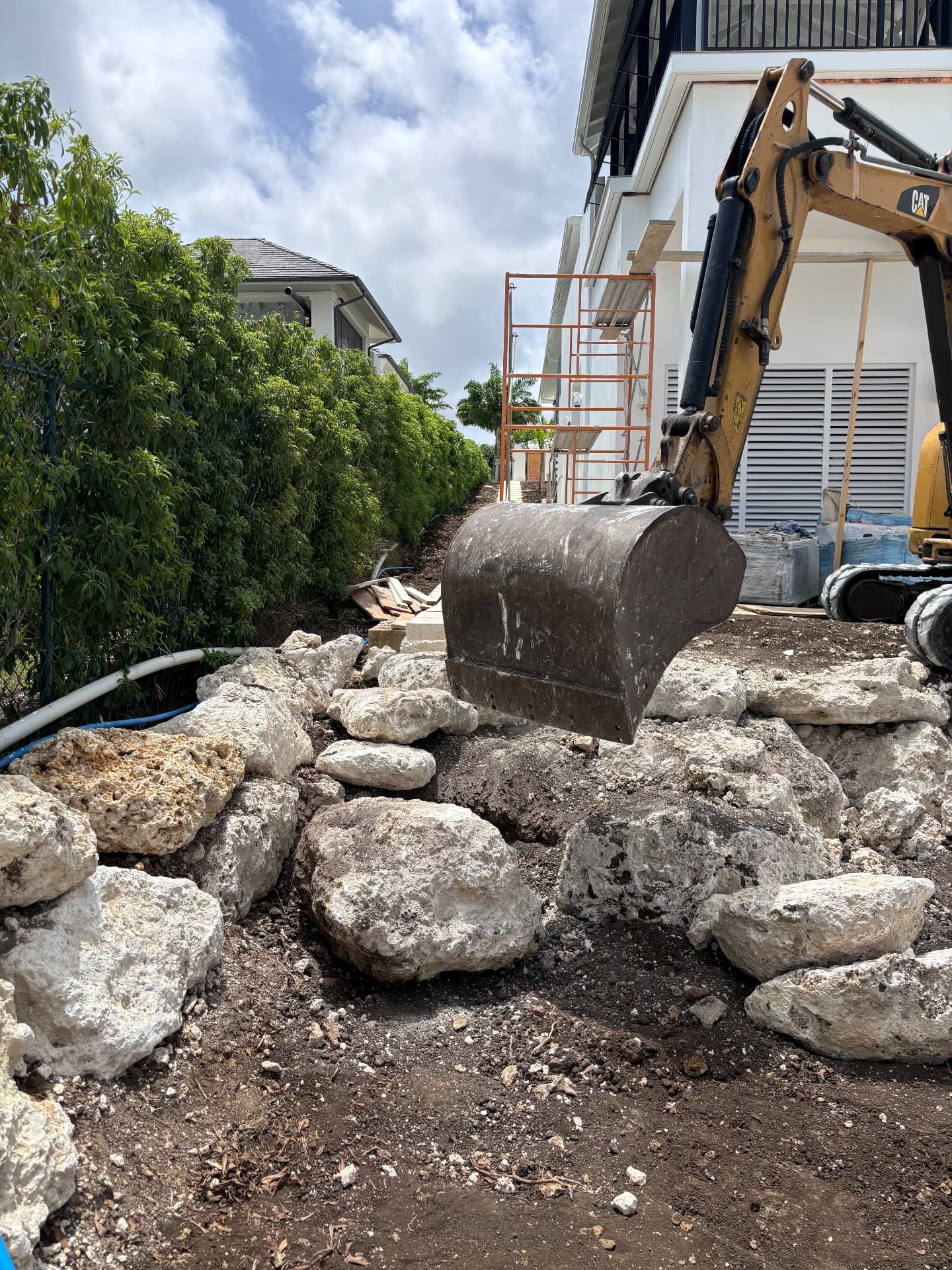 Excavator setting coral stone boulders alongside the villa in Barbados