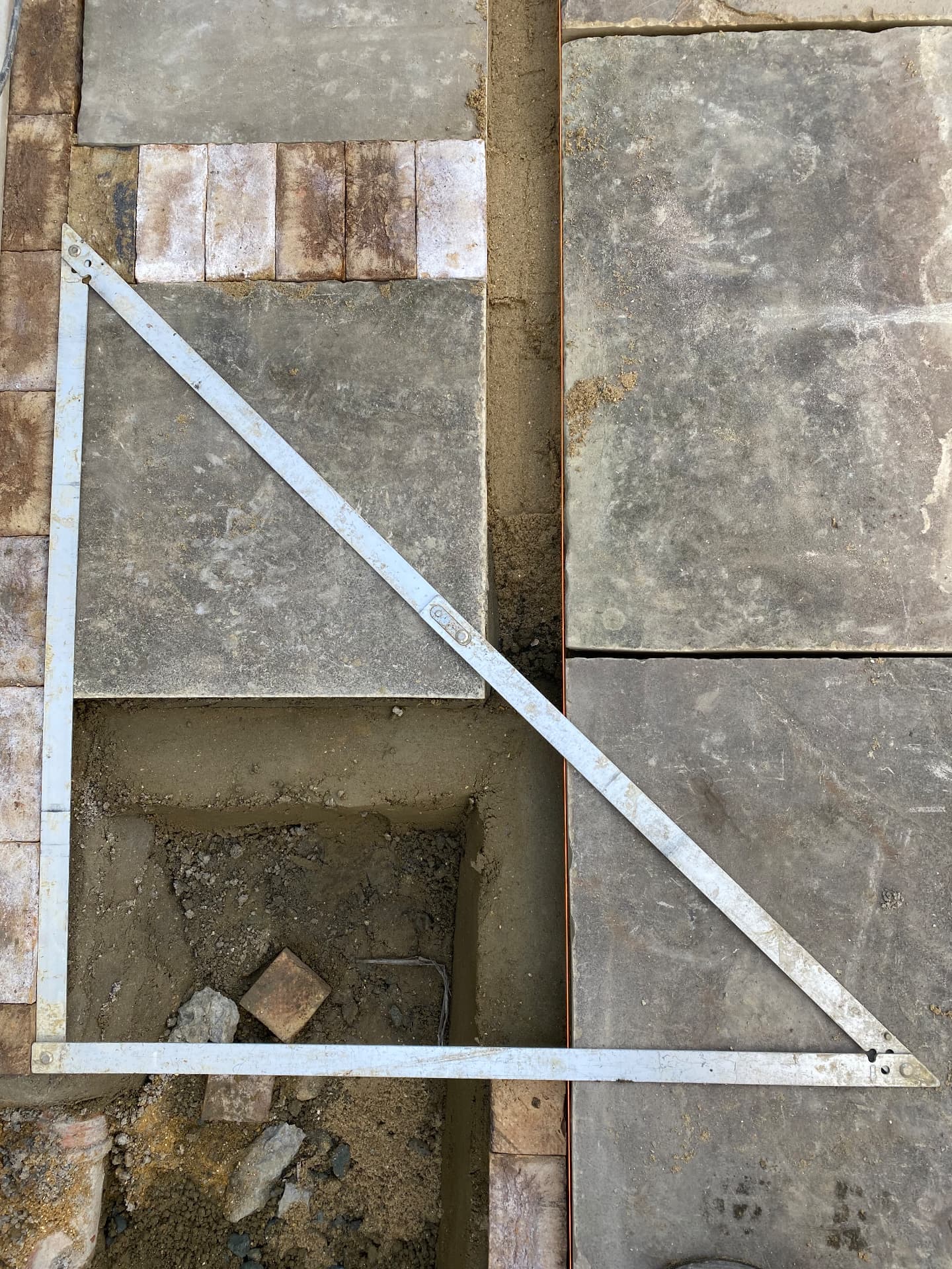 Stone paving set out on sand with a builder's square checking the corner