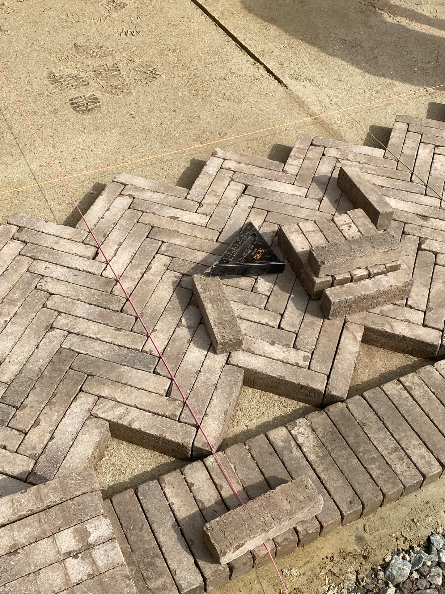 Setting out the herringbone brick pattern with a square and string lines